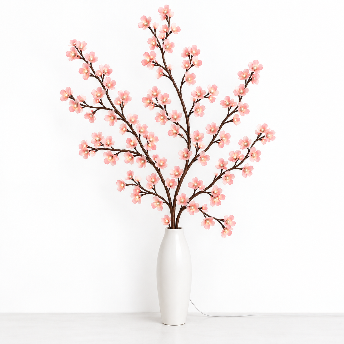 Cherry blossom branch lights displayed in a white vase